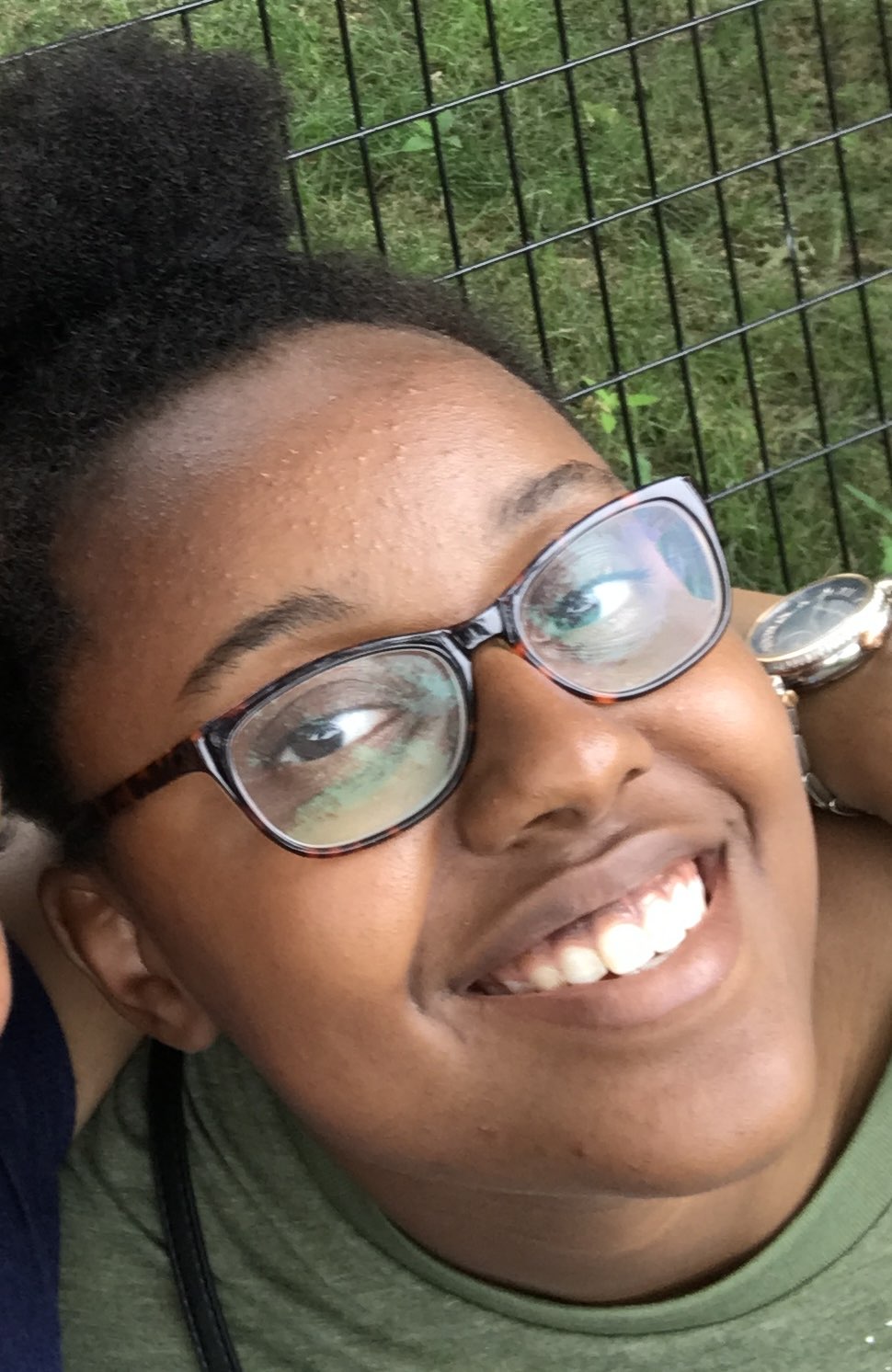 The face of a young, smiling, African-American woman with glasses.